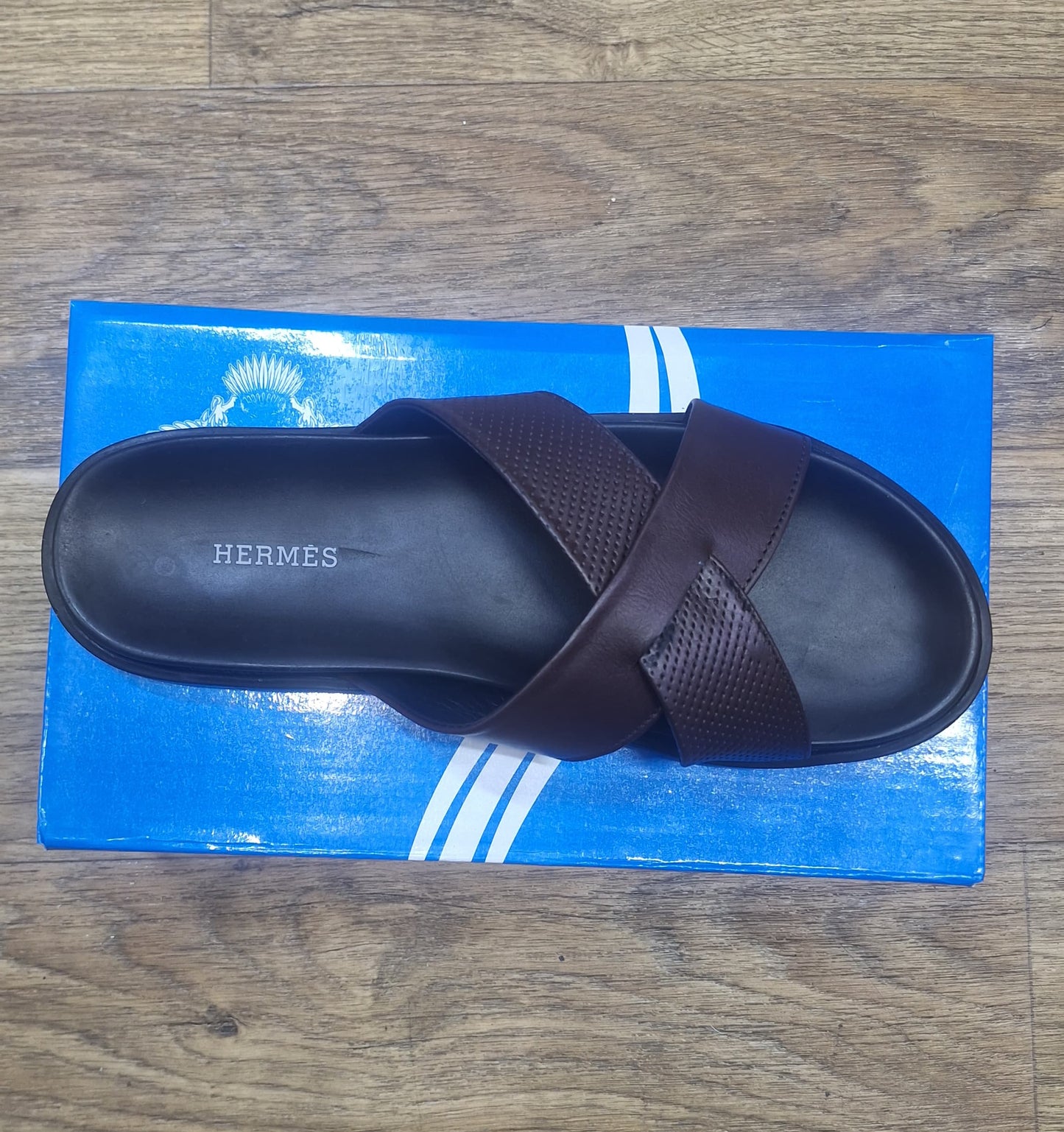 Brown sandal on a blue Hermès box on a wooden floor