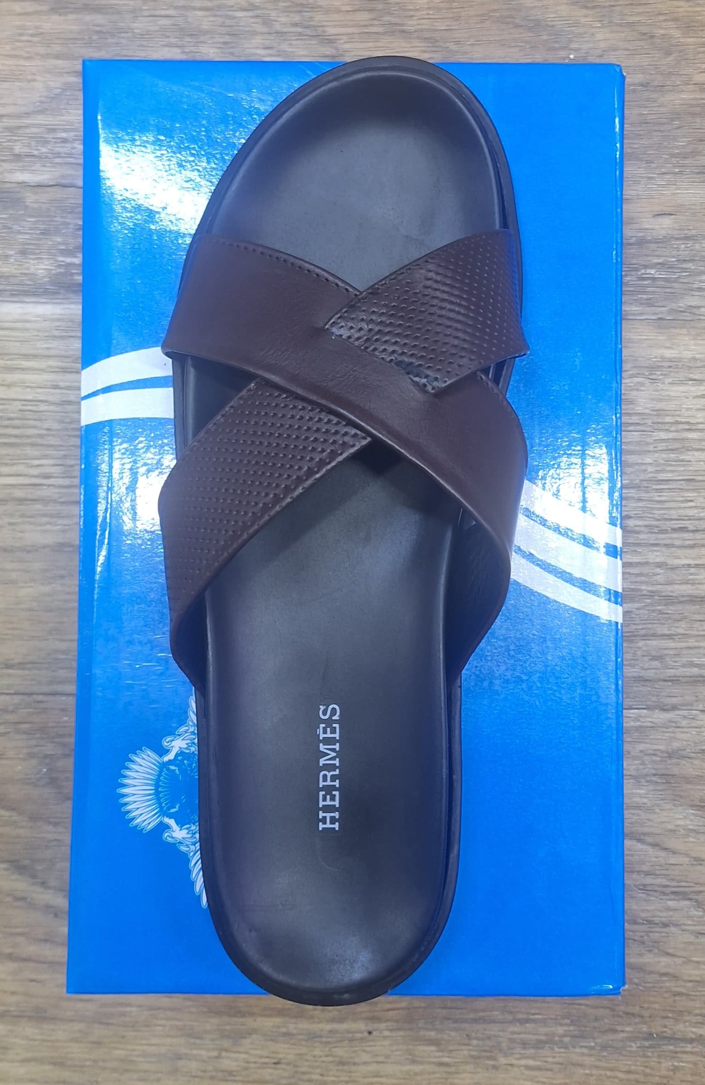 Brown sandal on a blue Hermes box on a wooden floor